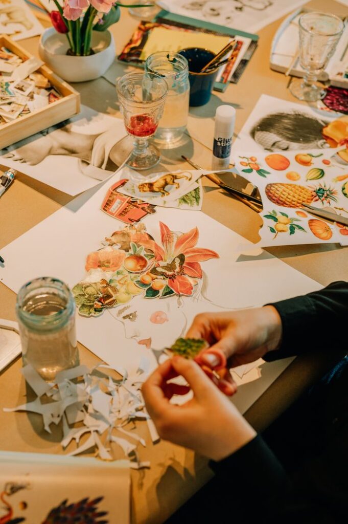 pexels photo 33808051 33808051 Hands creating an artistic collage with various cutouts on a table filled with art supplies.